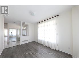A spacious room with white walls and a large window with white curtains.
