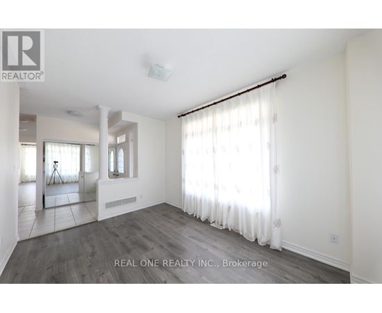 A spacious room with white walls and a large window with white curtains.