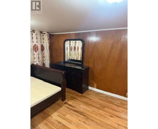A bedroom with a bed, nightstand, and a window with a curtain.