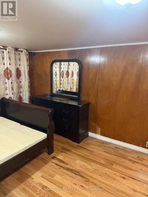 A bedroom with a bed, nightstand, and a window with a curtain.
