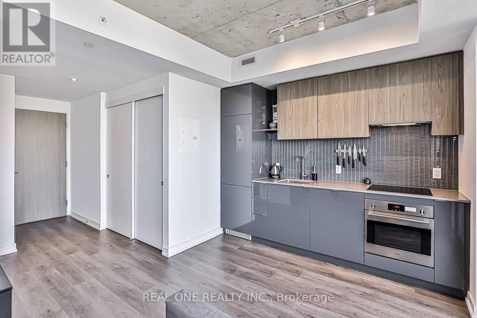 A modern kitchen with wooden cabinets and a grey backsplash.