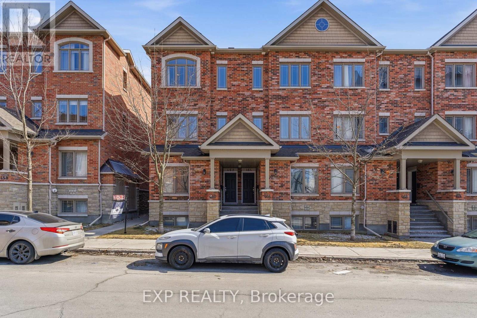 A white car is parked in front of a brick apartment building.