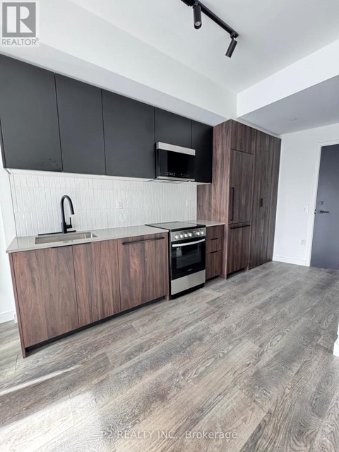 A modern kitchen with wooden cabinets and a grey floor.
