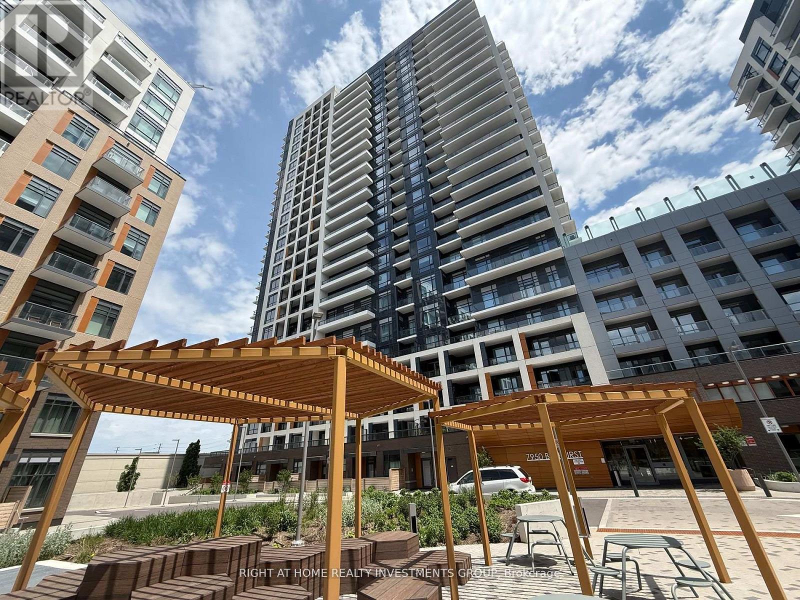A wooden pergola is in the foreground of a city scene with apartment buildings.