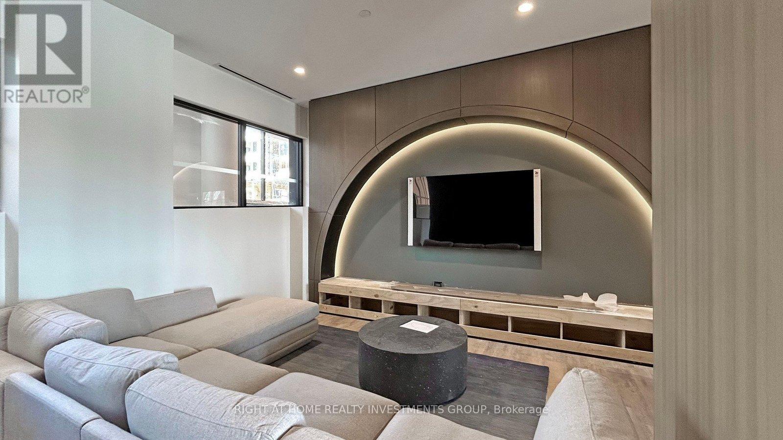 A modern living room with a grey sofa and a flat screen TV mounted on the wall.