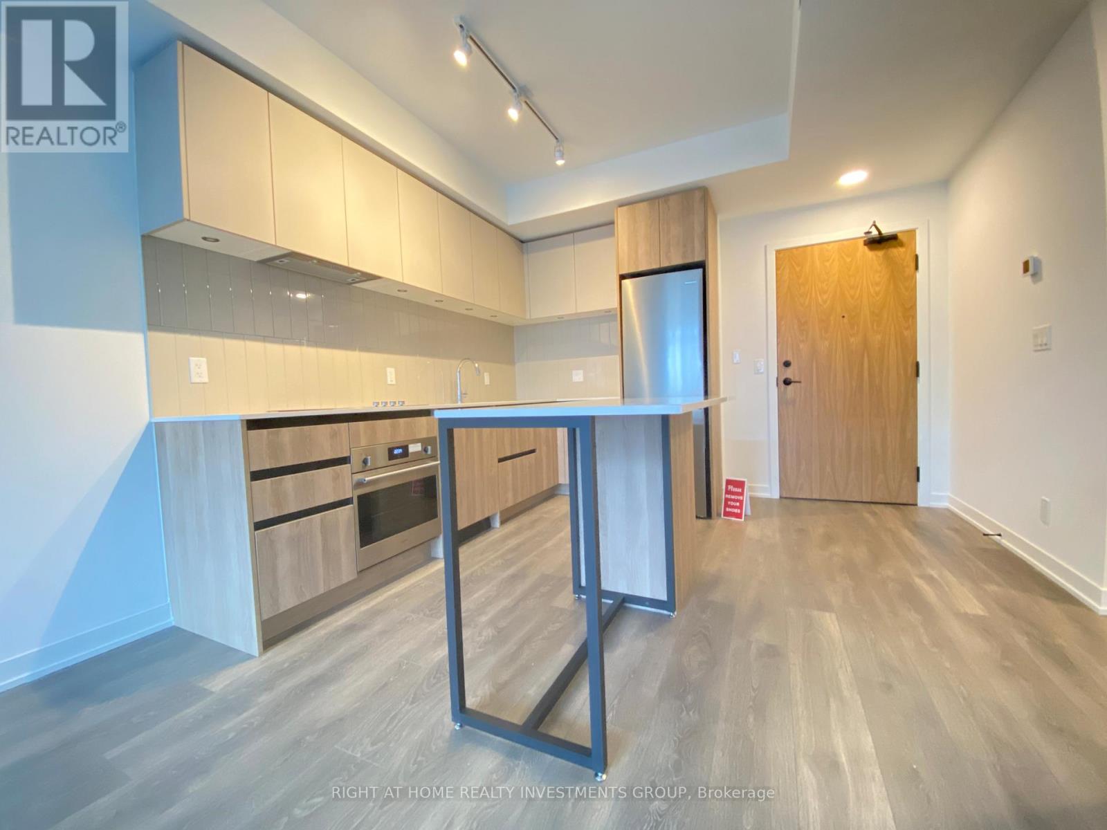 A modern kitchen with wooden cabinets and a stainless steel refrigerator.