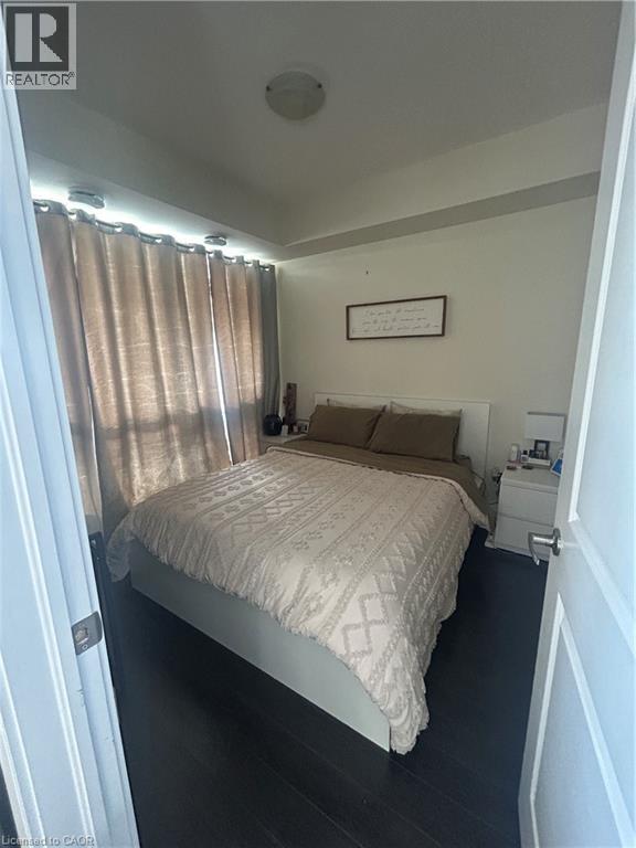 A bedroom with a bed, nightstand, and window with curtains.