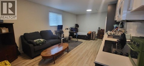 A living room with a black couch and a wooden coffee table.