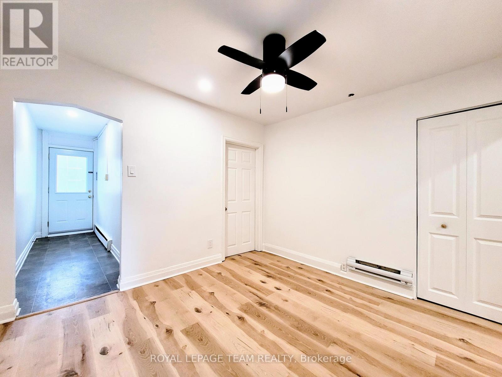 A room with a ceiling fan and wooden flooring.
