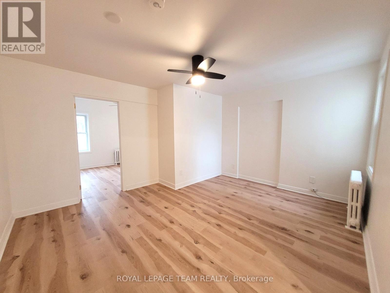 A room with wooden flooring and a ceiling fan.