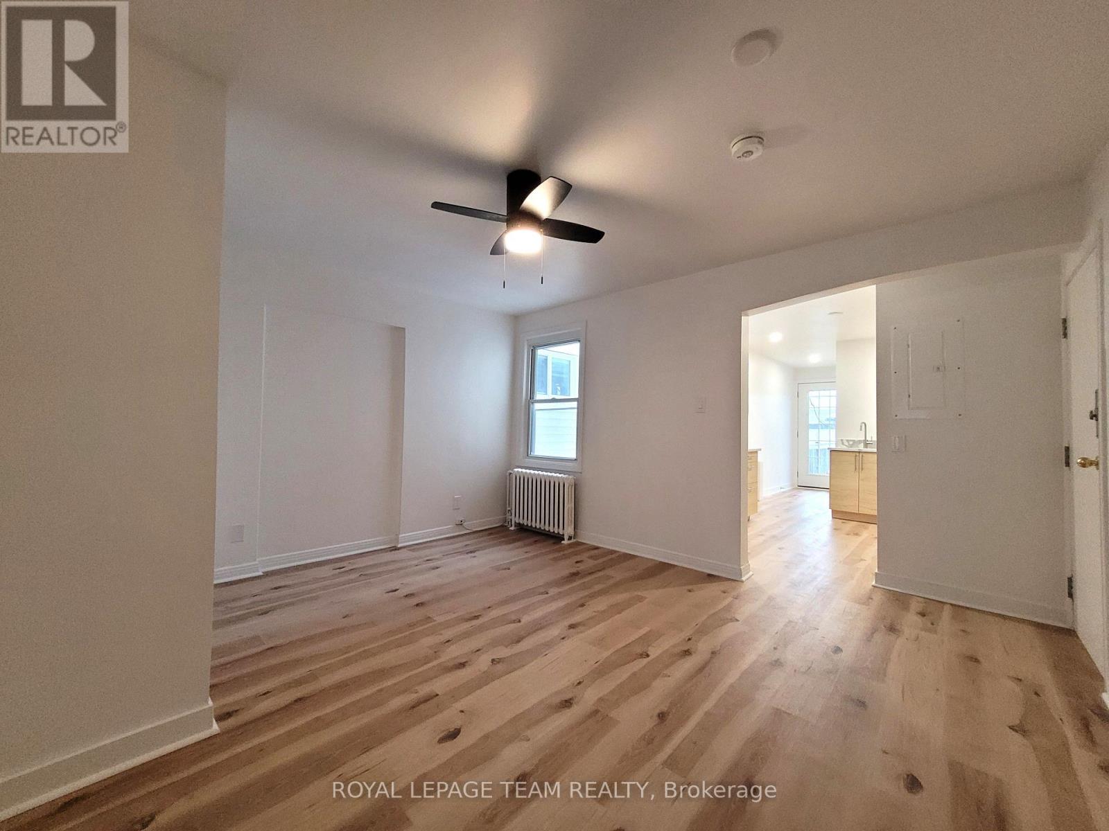 A room with wooden flooring and a ceiling fan.