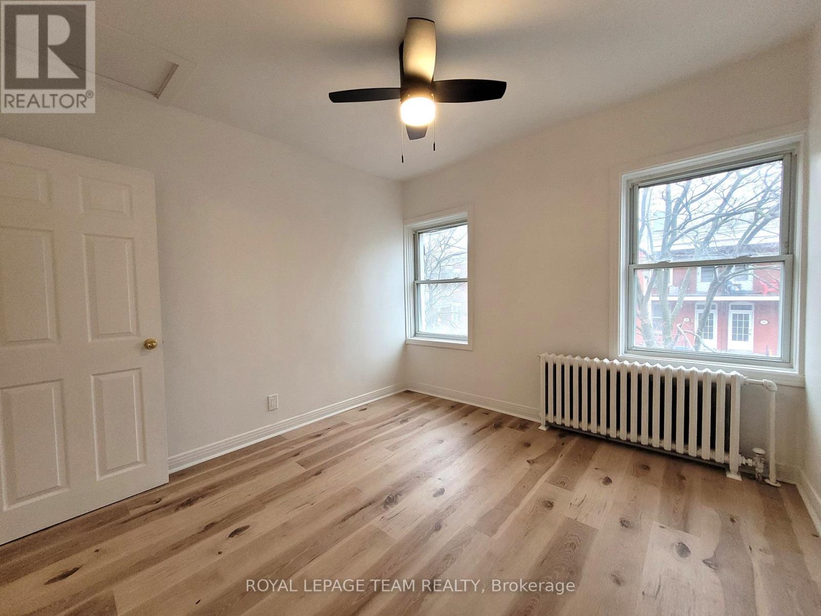 A room with a ceiling fan and a window with a view of a building outside.