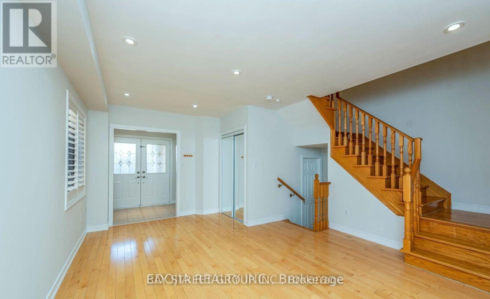 A spacious room with wooden floors and a staircase leading to another level.