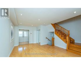 A spacious room with wooden floors and a staircase leading to another level.