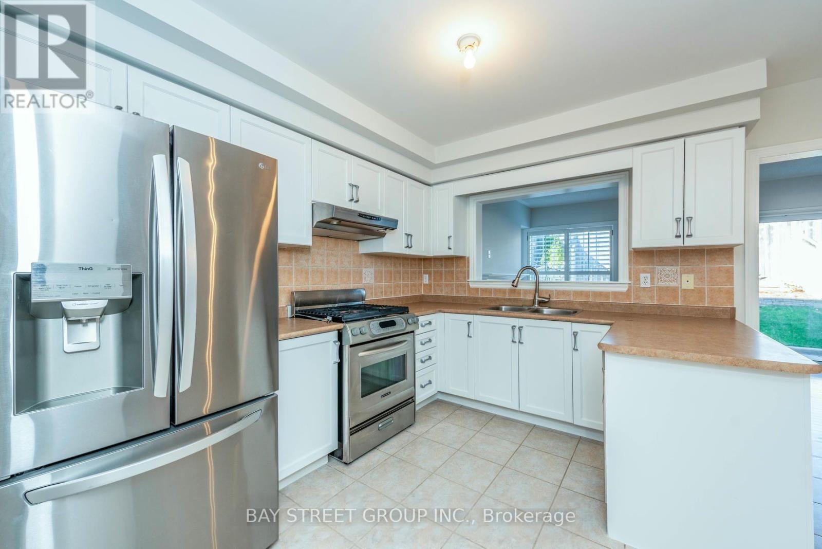 A kitchen with white cabinets and a stainless steel refrigerator.