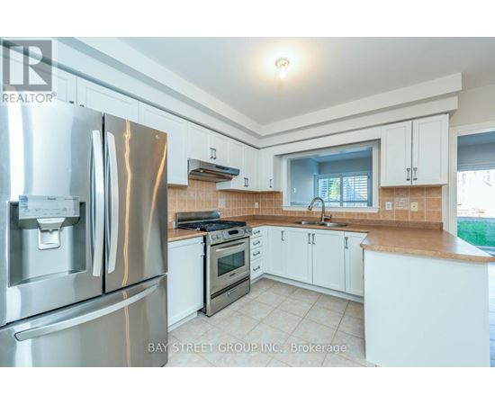 A kitchen with white cabinets and a stainless steel refrigerator.