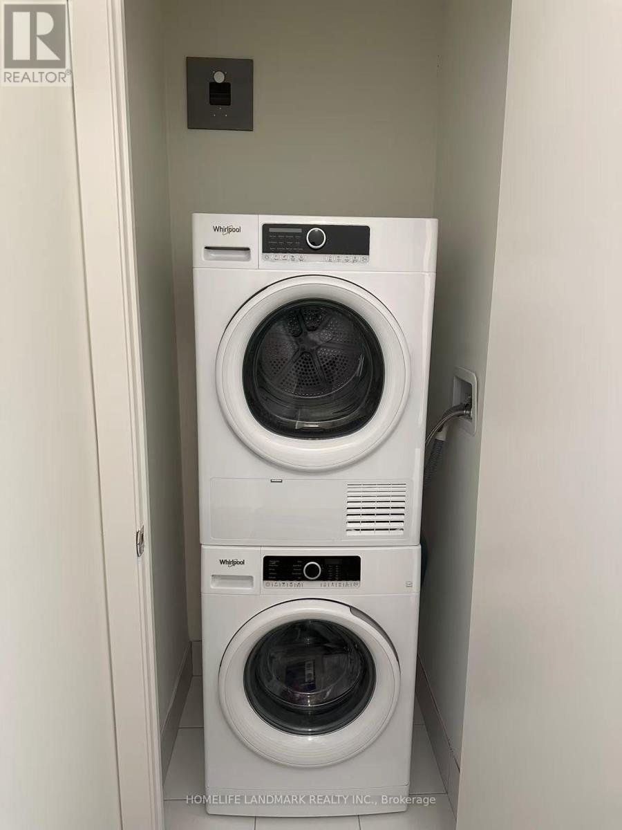 A stack of two white Whirlpool washing machines in a small room.