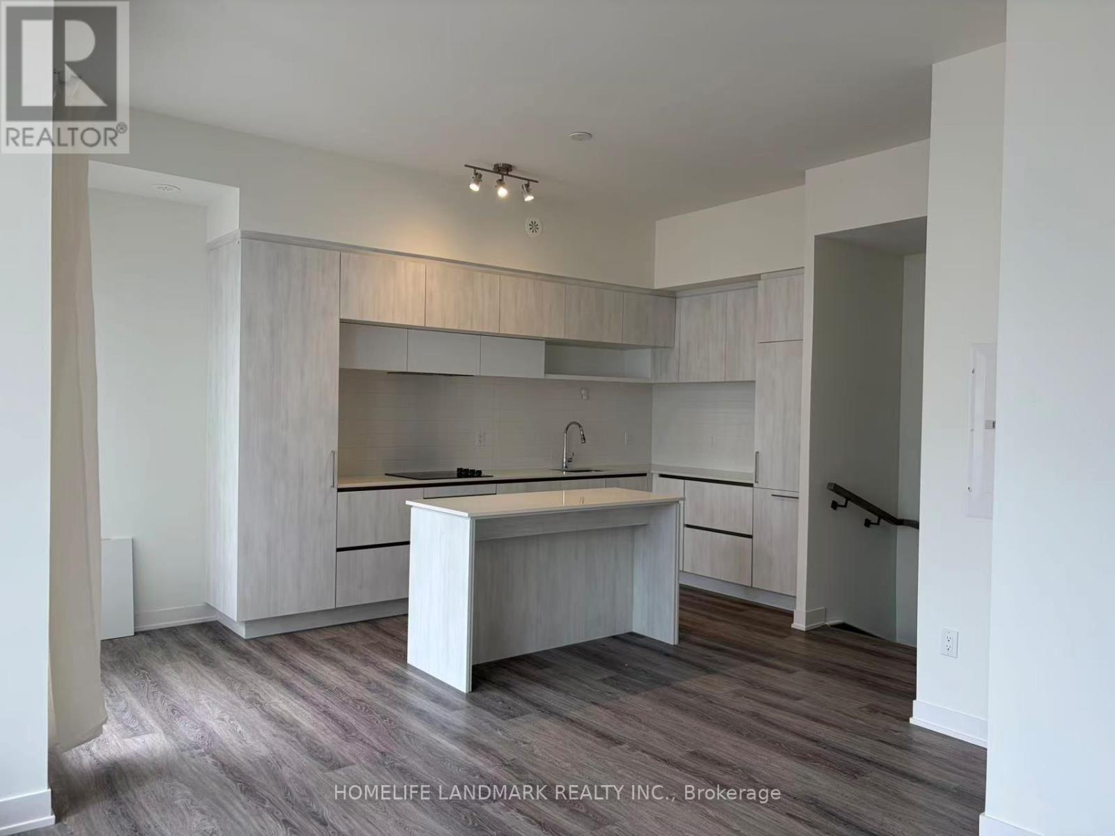 A kitchen with white cabinets and a wooden floor.