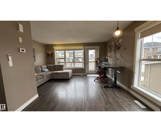 A living room with a couch, a chair, and a dining table.