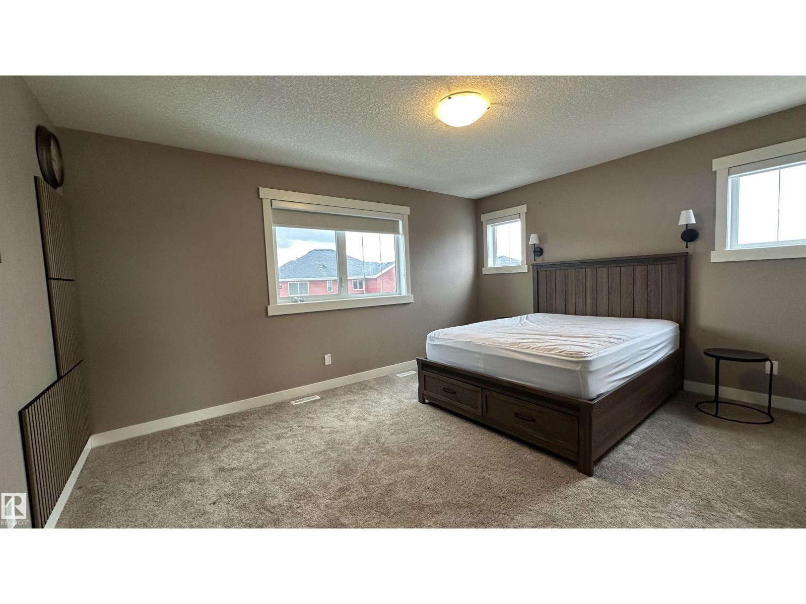 A bedroom with a bed, nightstand, and window.