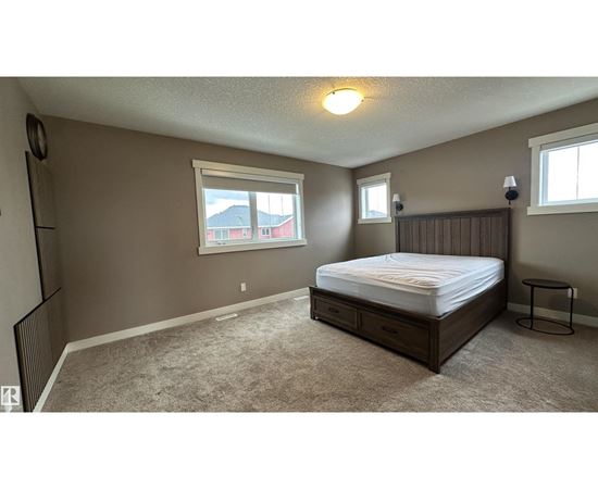 A bedroom with a bed, nightstand, and window.