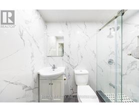 A bathroom with marble walls and a glass shower stall.
