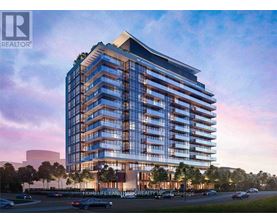 A modern apartment building with a glass facade and a parking lot in front.