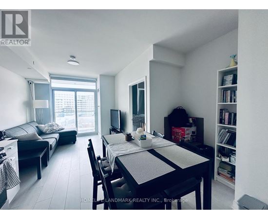 A dining room with a table set for two and a living room with a couch and television in the background.