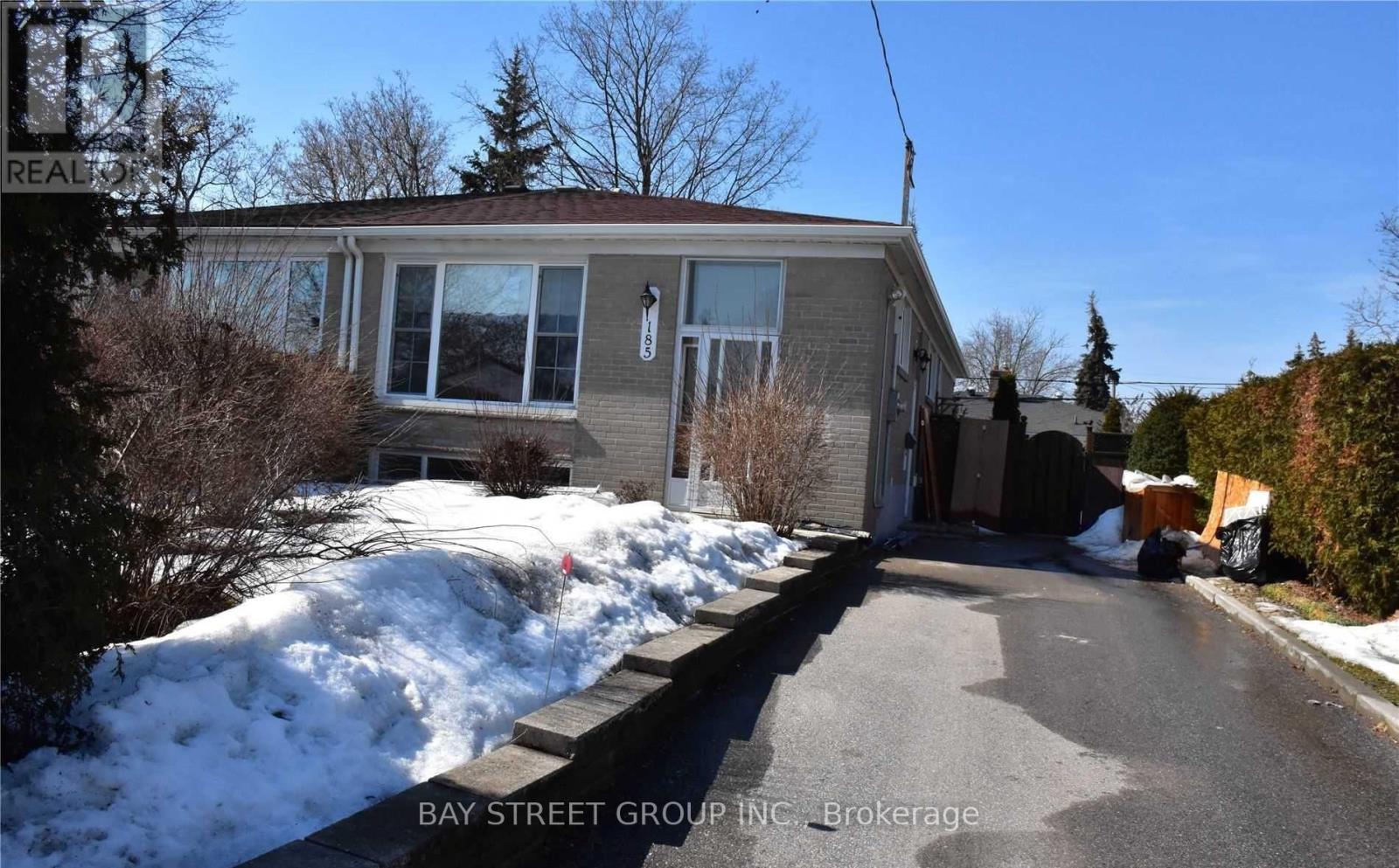 A house with a snow-covered ground and a sign that says "REALTOR" in the foreground.