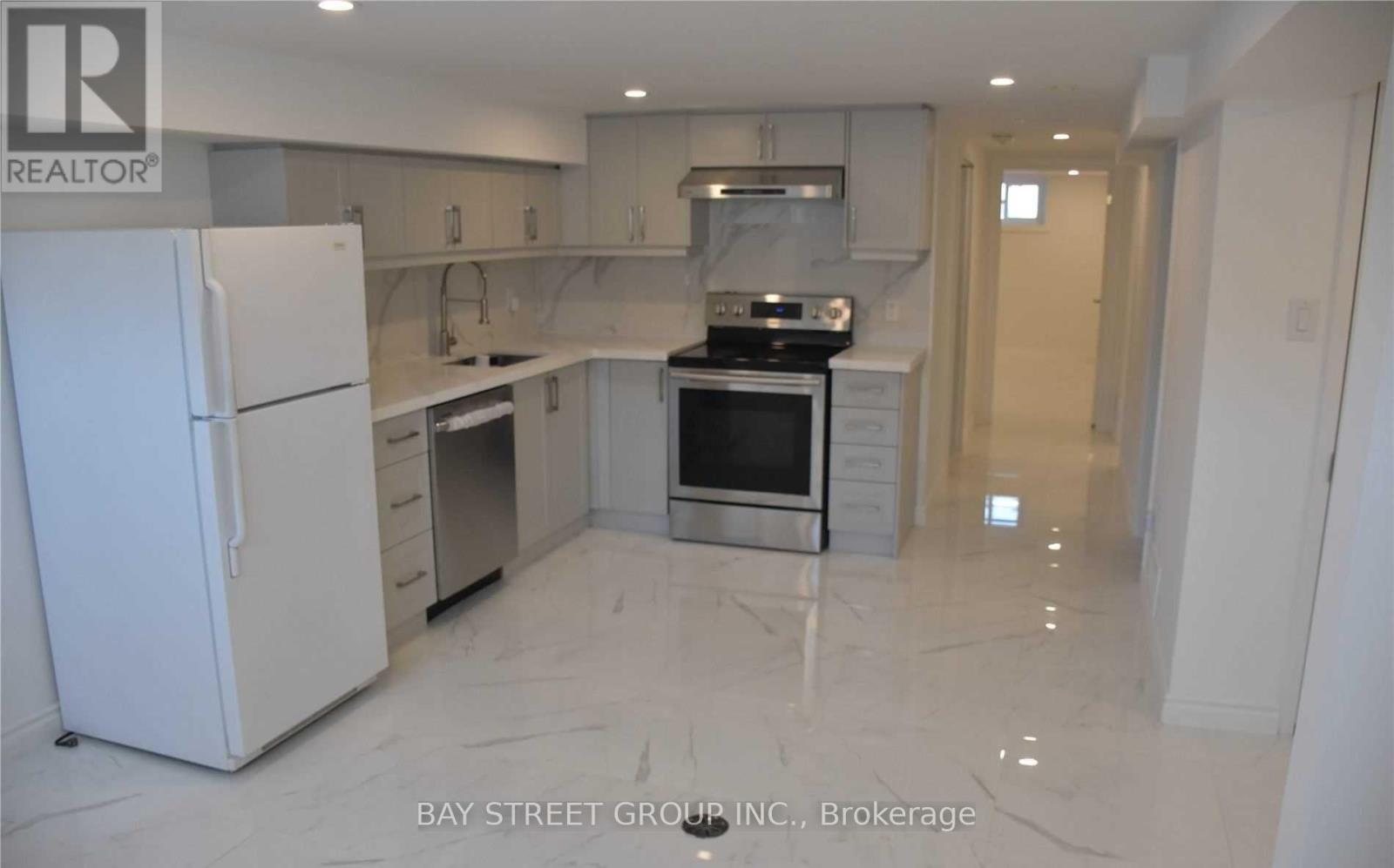 A white refrigerator is in a kitchen with marble flooring.