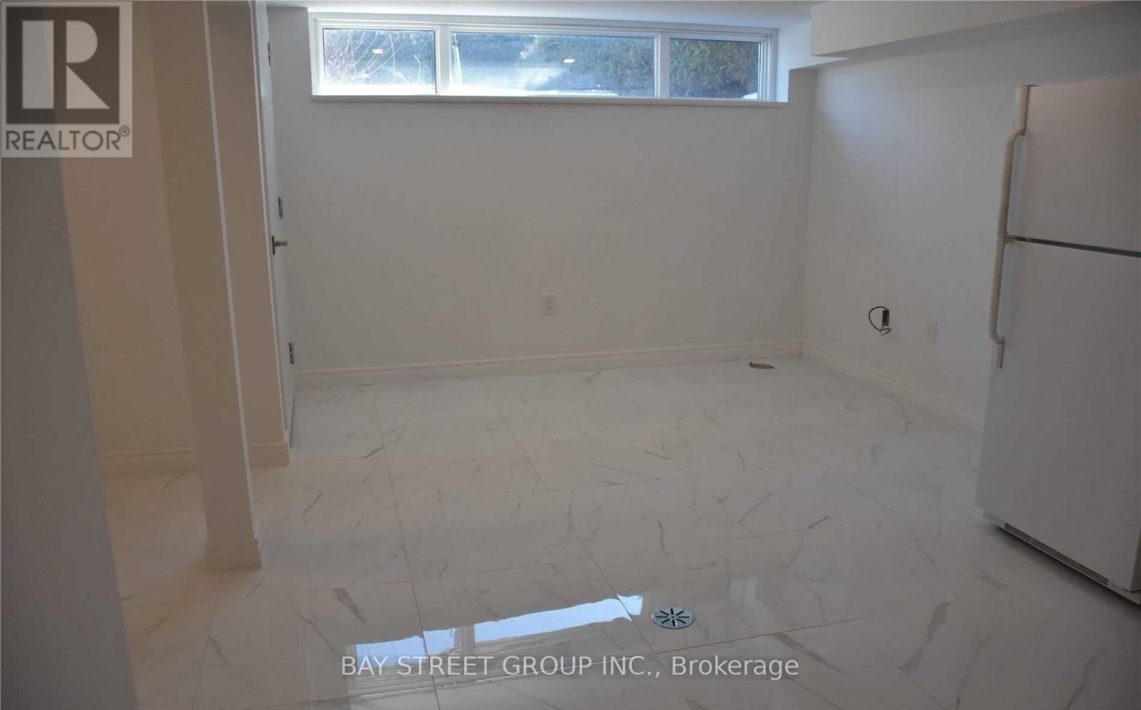 A room with a white refrigerator and a window.