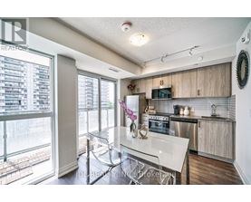 A modern kitchen with a glass table and stainless steel appliances.