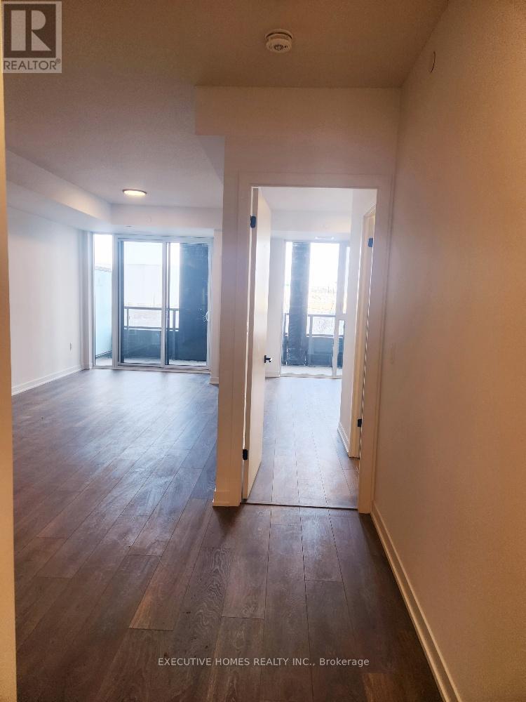 A room with wood floors and white walls, with a doorway leading to another room.