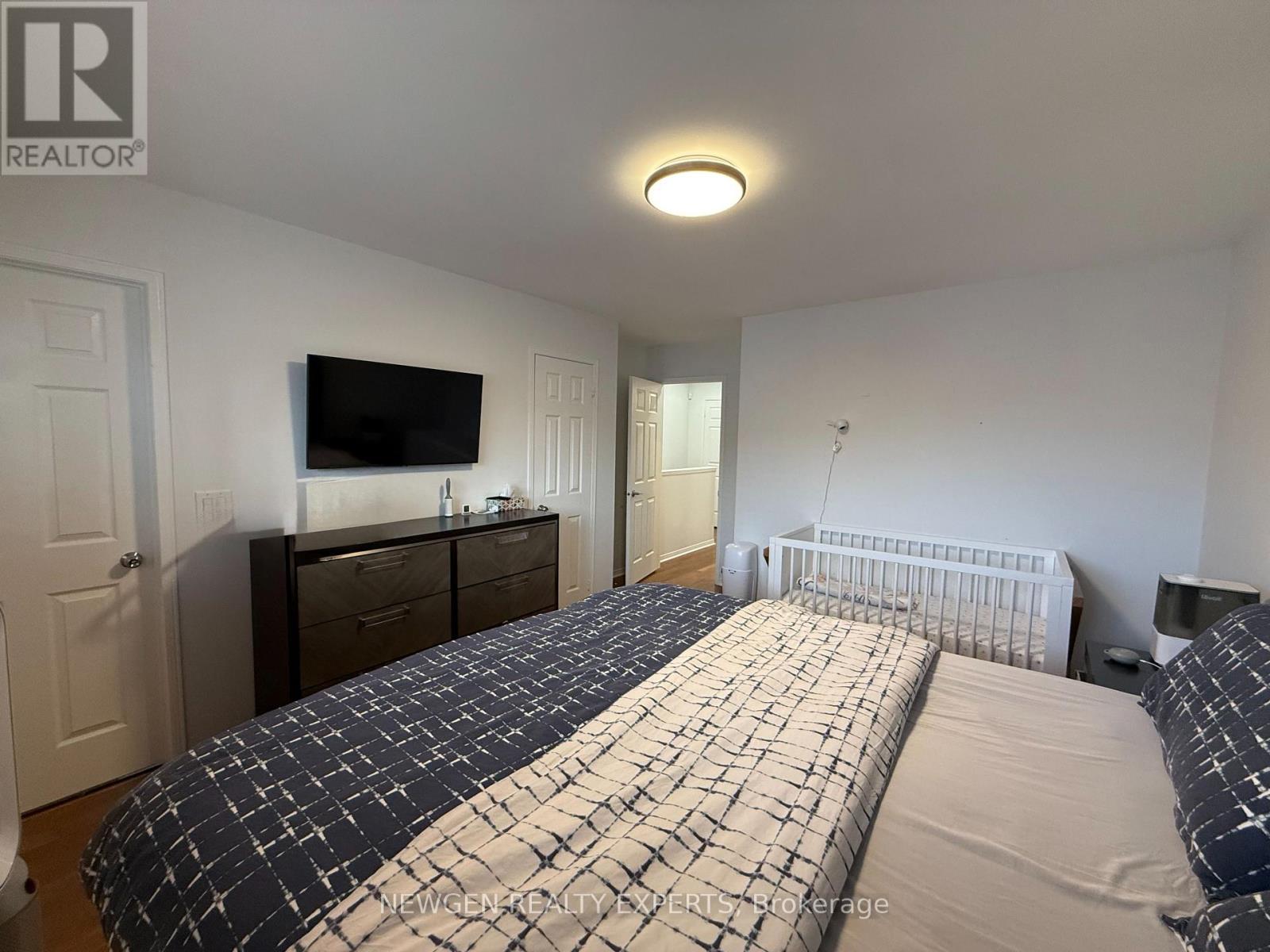 A bedroom with a large bed and a flat screen TV mounted on the wall.