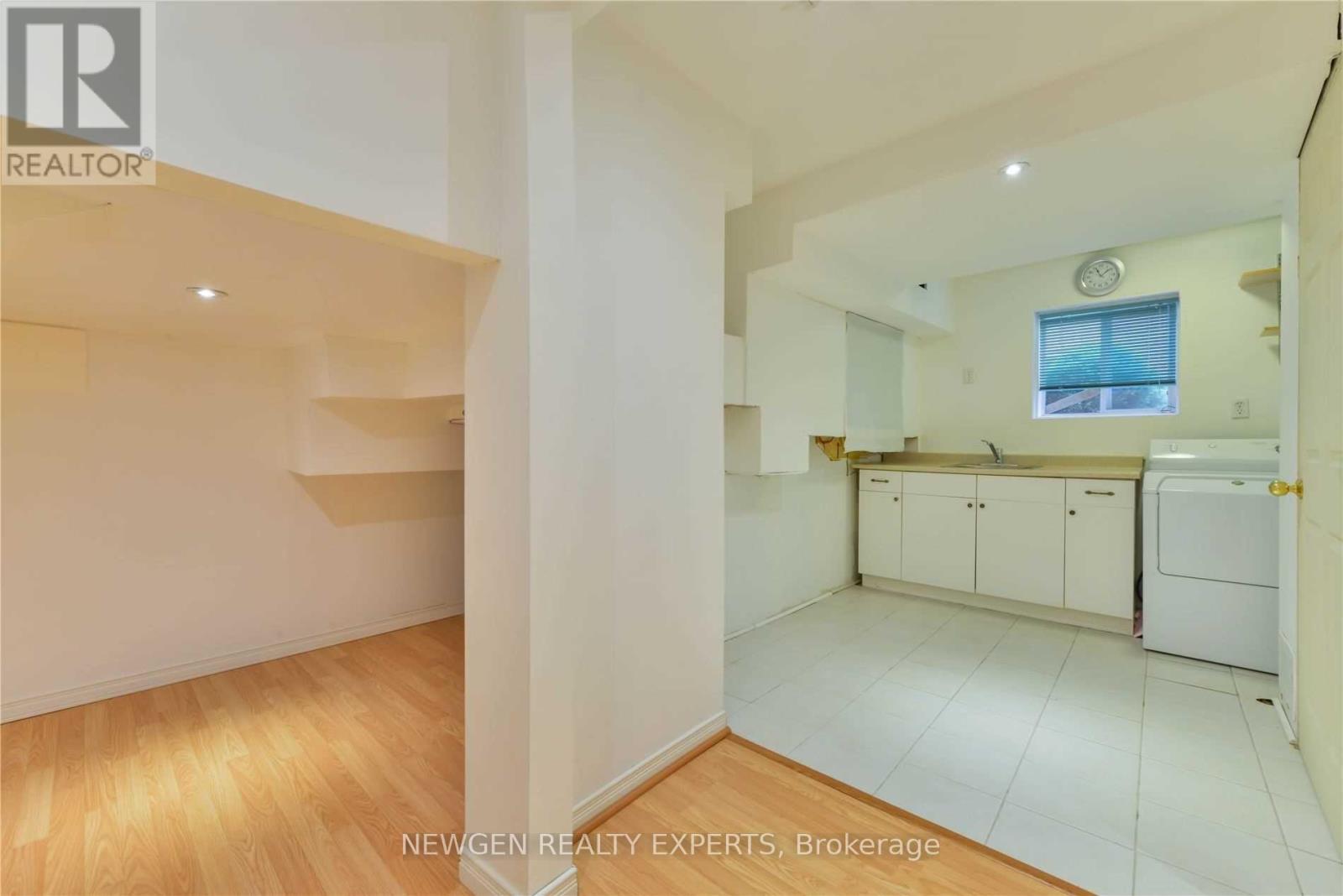 A spacious, empty room with wooden flooring and white walls.