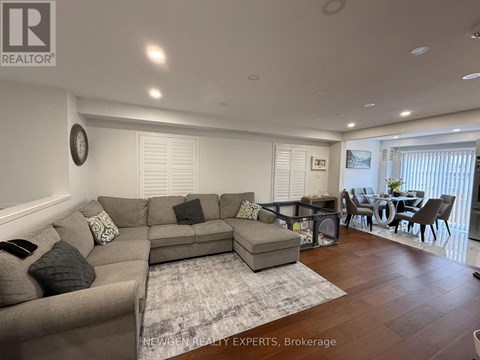 A spacious living room with a grey sofa set and a dining table with chairs.