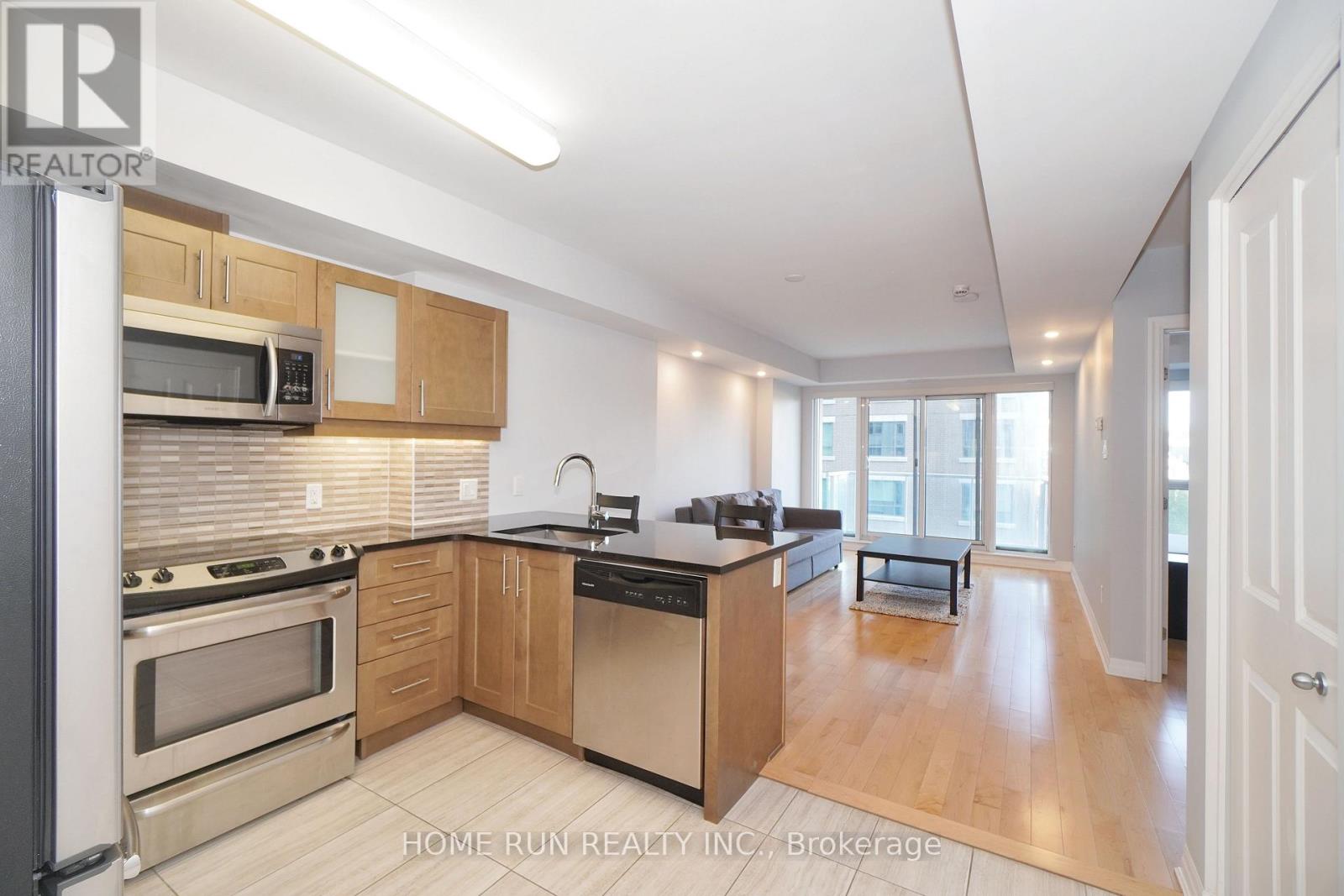 A well-lit kitchen with wooden cabinets and stainless steel appliances.