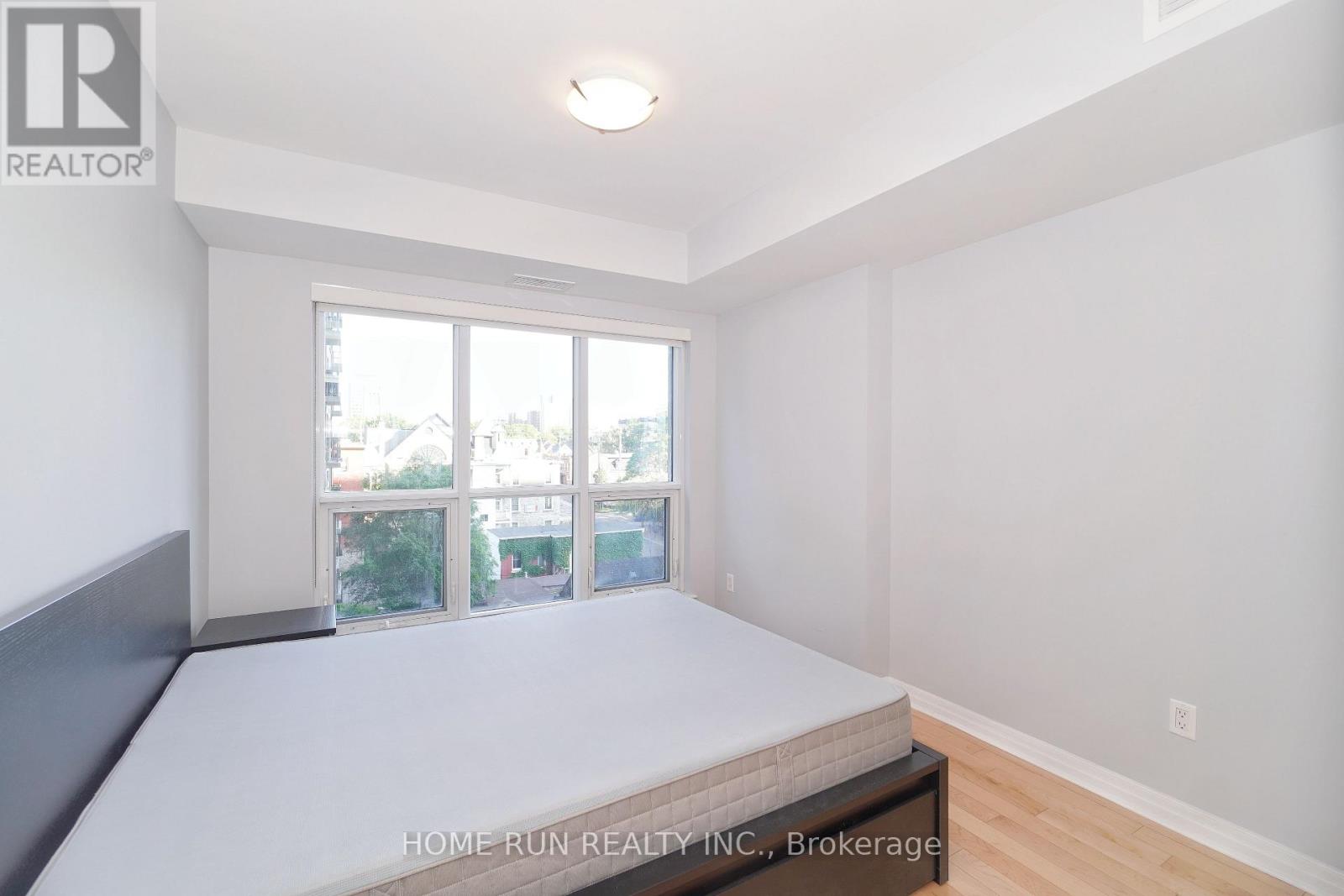 A bedroom with a large bed and a window overlooking a street.