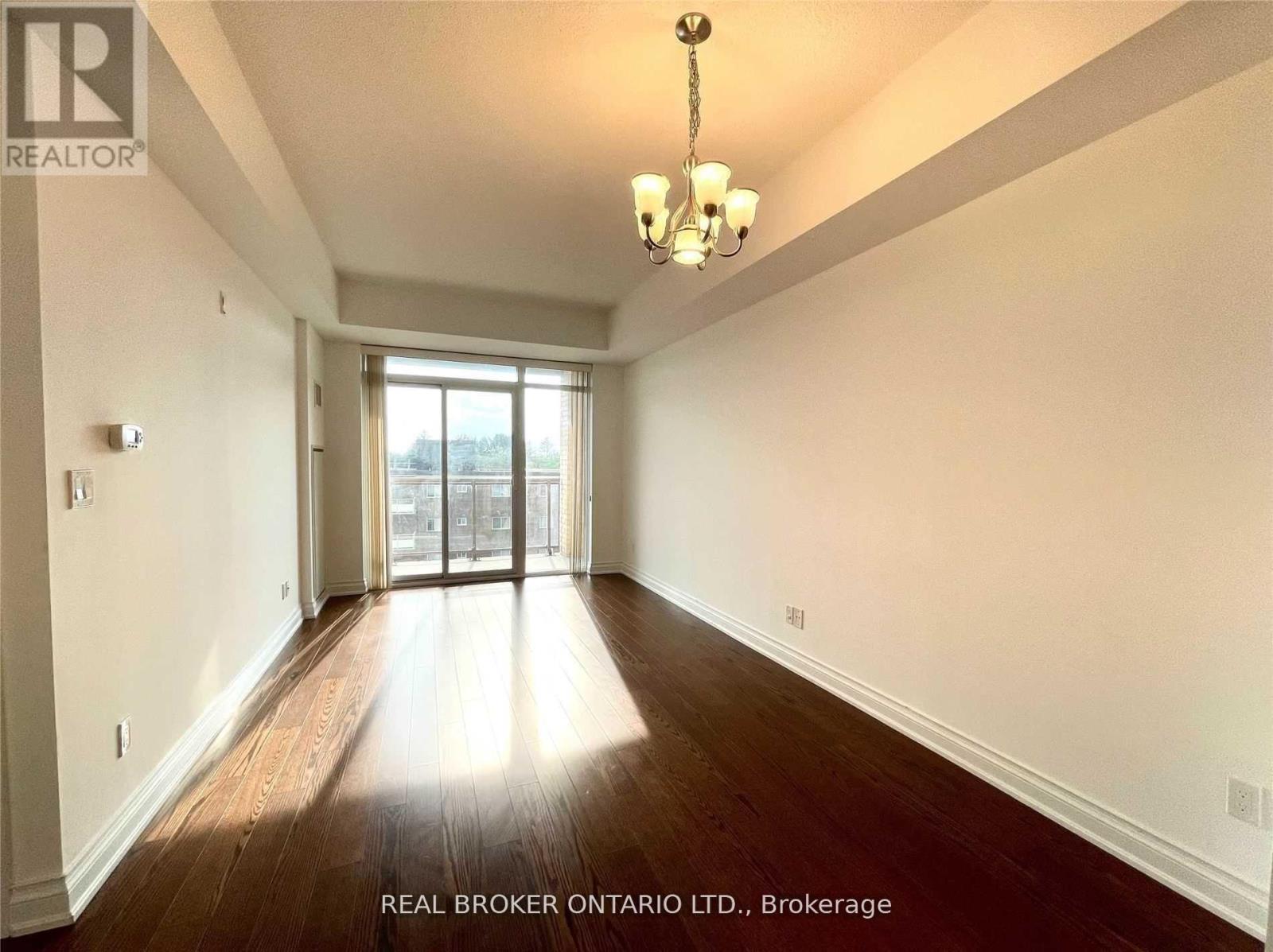 A spacious room with wood flooring and a chandelier.