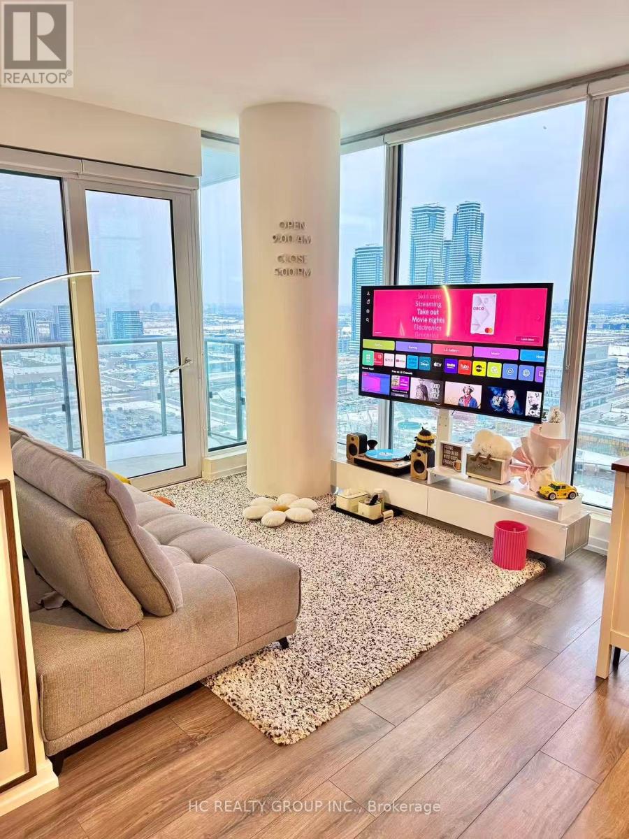 A modern living room with a large flat screen TV and a view of the city.