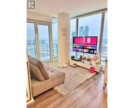 A modern living room with a large flat screen TV and a view of the city.