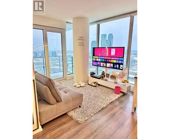 A modern living room with a large flat screen TV and a view of the city.