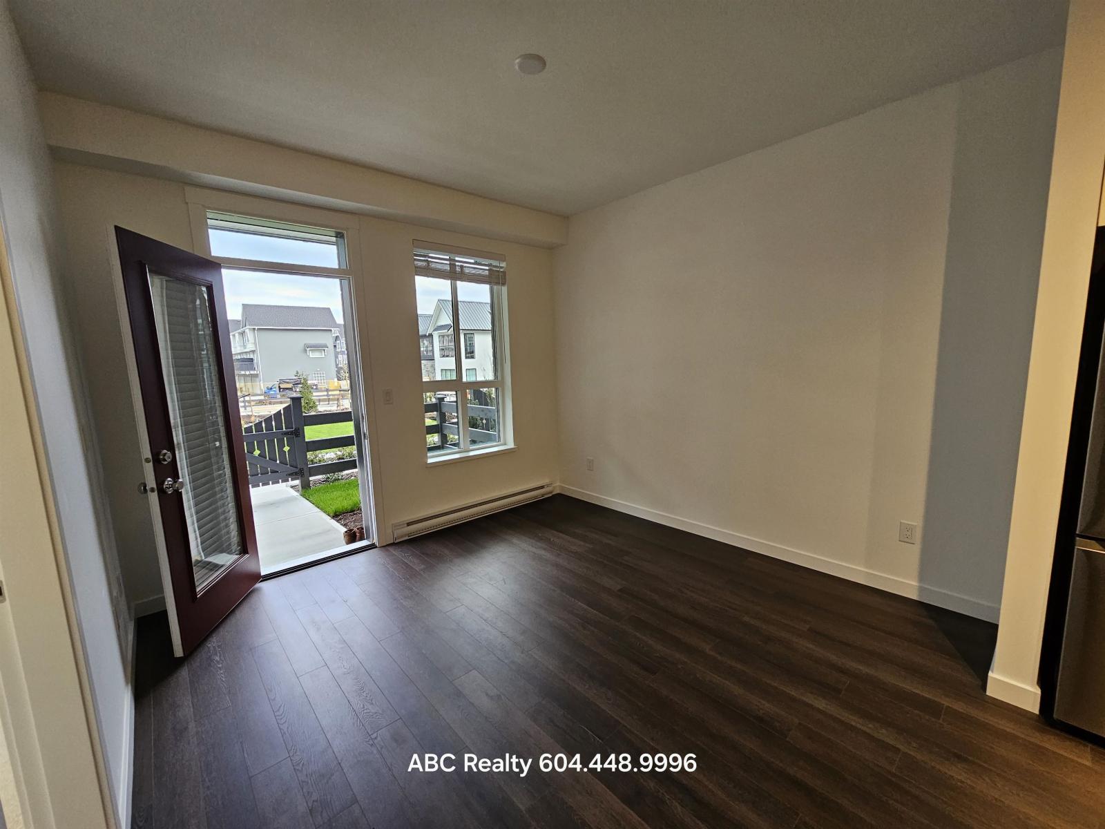 A room with wooden floors and a large window overlooking a street.
