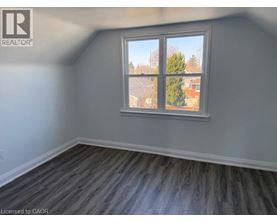 A room with a window showing a view of a tree and a building outside.