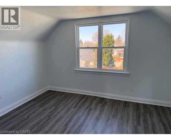 A room with a window showing a view of a tree and a building outside.