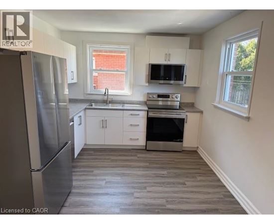 A kitchen with a refrigerator, sink, oven, and microwave.