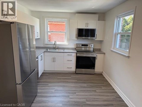 A kitchen with a refrigerator, sink, oven, and microwave.