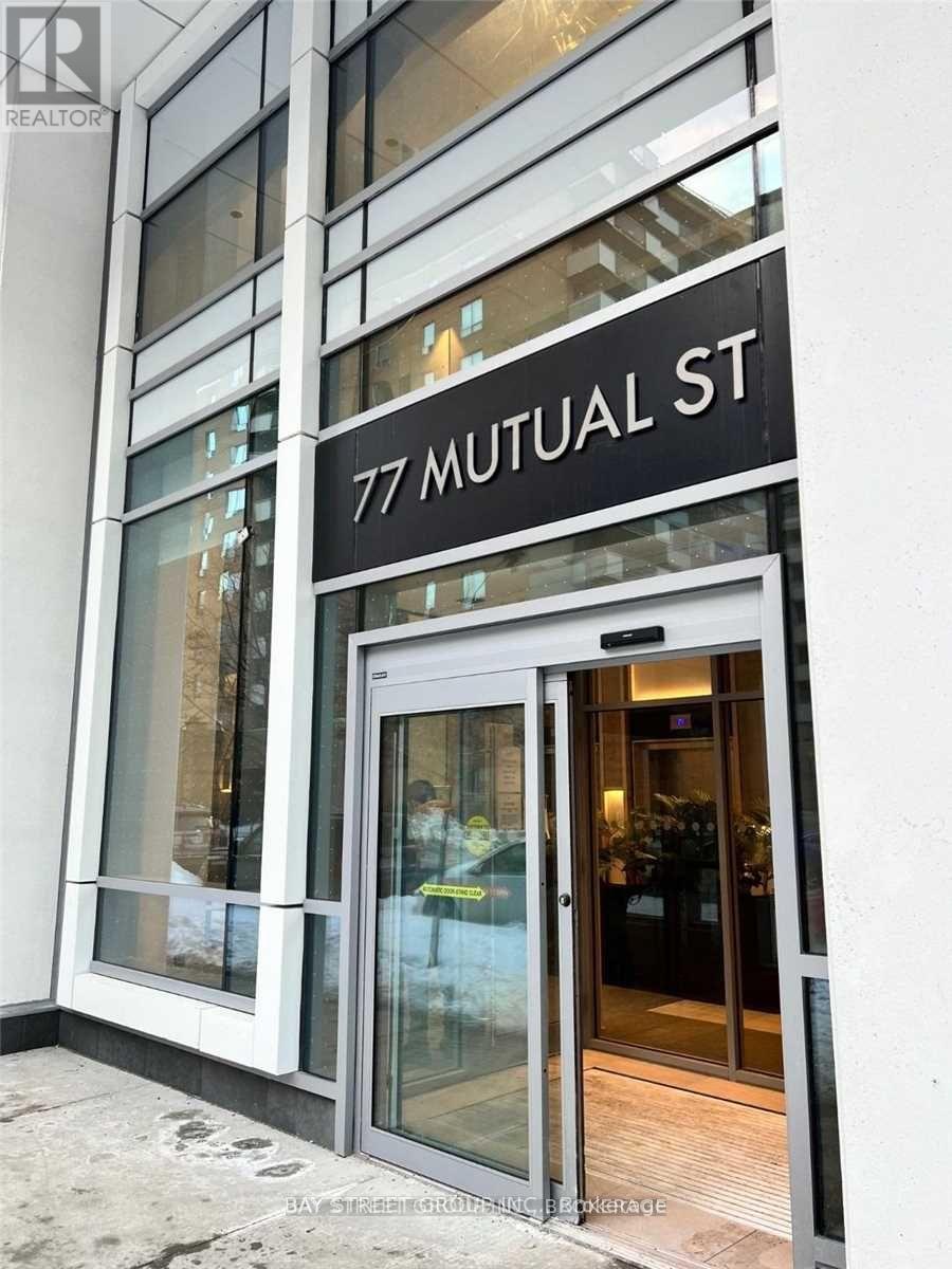 The entrance to a building with a glass door and a sign that reads "77 Mutual St."