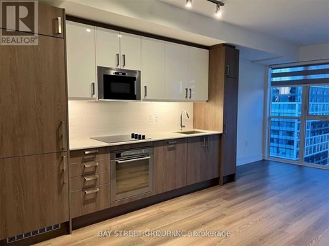 A modern kitchen with wooden cabinets and a large window.