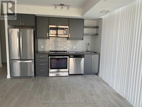 A modern kitchen with stainless steel appliances and a wooden floor.
